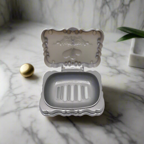Small silver metal soap dish with decorative back on a white background