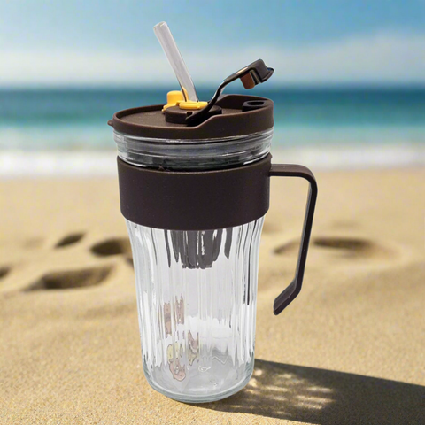 Clear glass tumbler with brown lid and handle on a white background
