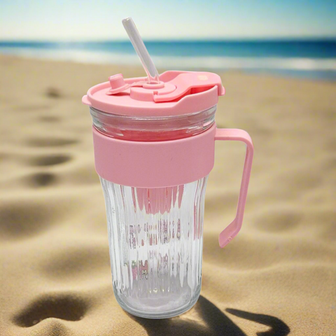Pink lid and handle tumbler with straw on sandy beach